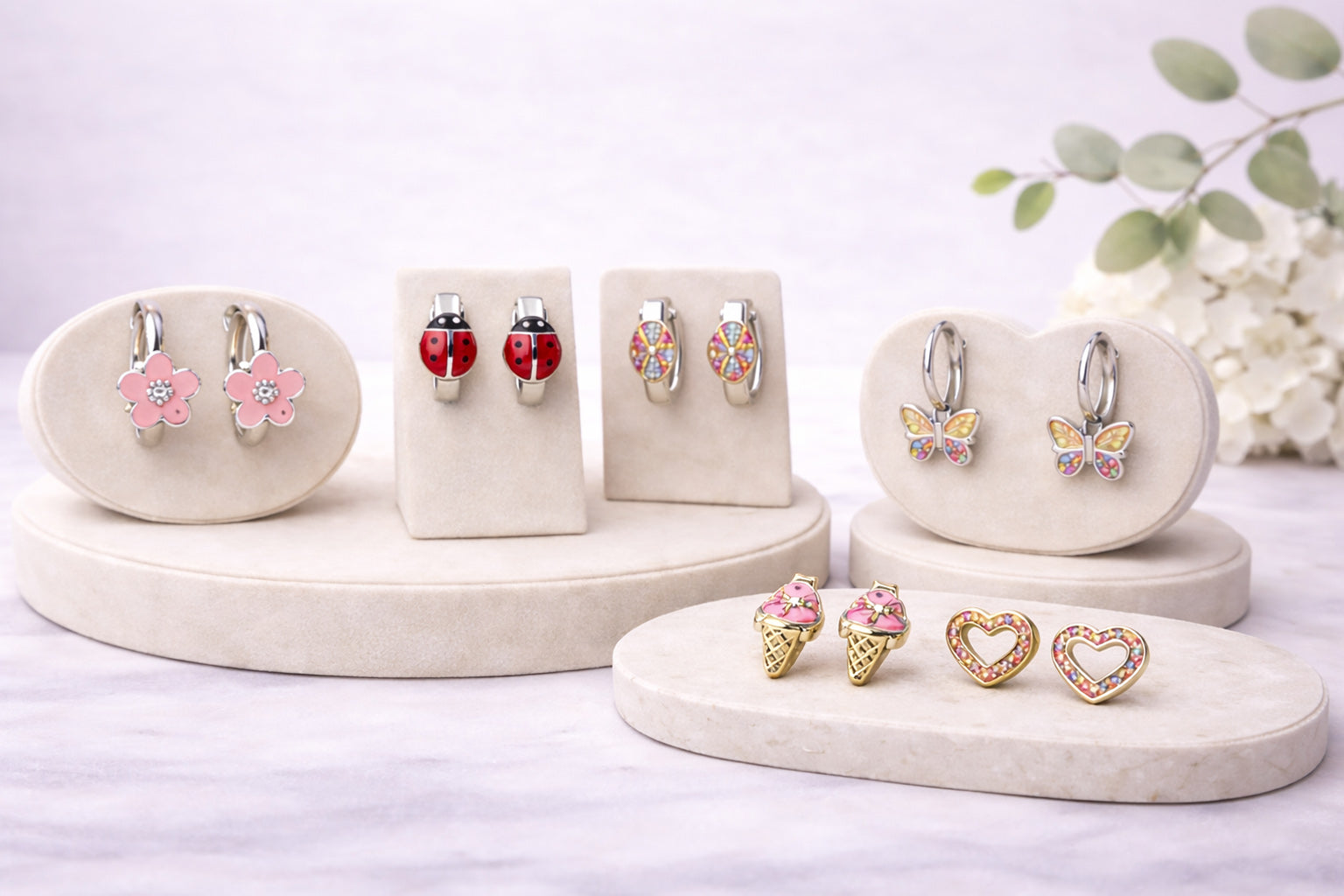 Verschiedene Kinderohrringe aus 925 Sterling Silber mit bunten Motiven auf Schmuckständern