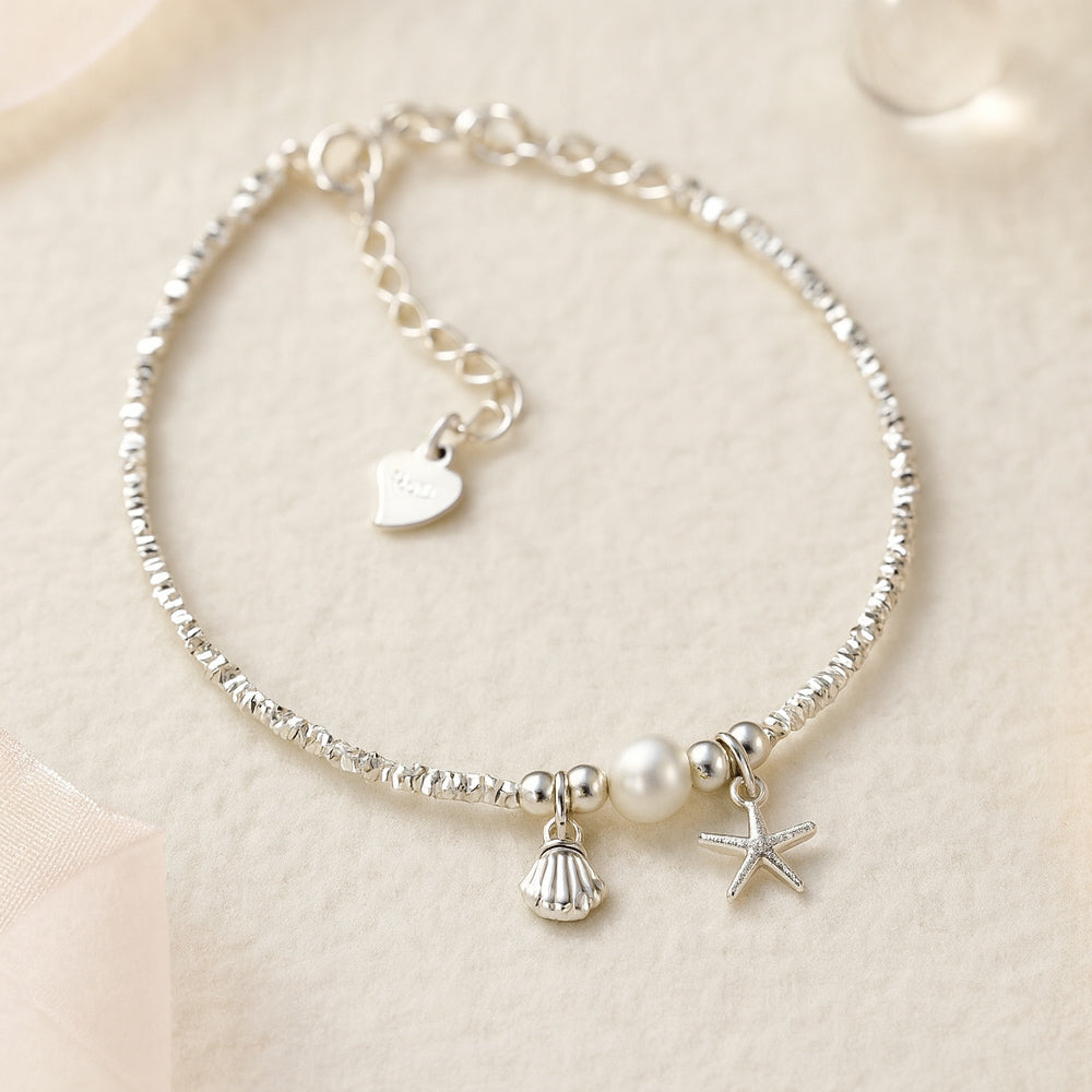 Zartes Silberarmband mit Perle, Seestern- und Muschel-Anhänger - maritimes Damenarmband im eleganten Design, perfektes Accessoire für Sommer, Strand und Alltag.