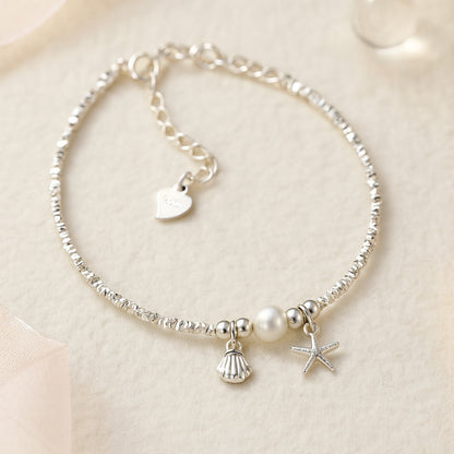 Zartes Silberarmband mit Perle, Seestern- und Muschel-Anhänger - maritimes Damenarmband im eleganten Design, perfektes Accessoire für Sommer, Strand und Alltag.