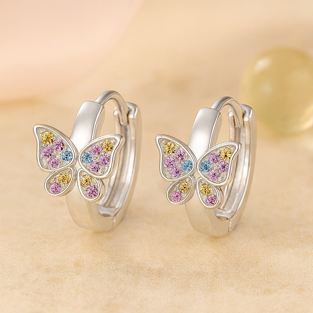 Silberne Creolen mit bunten Schmetterlingsanhängern und funkelnden Zirkonia in Rosa, Gelb und Blau - verspielter Schmuck für Mädchen.