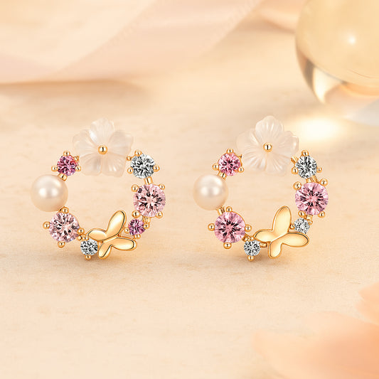 Elegante goldene Ohrstecker im Blumenkranz-Design mit rosa und weißen Zirkonia, Perle, Blüte und Schmetterlings-Element - romantischer Damenschmuck.
